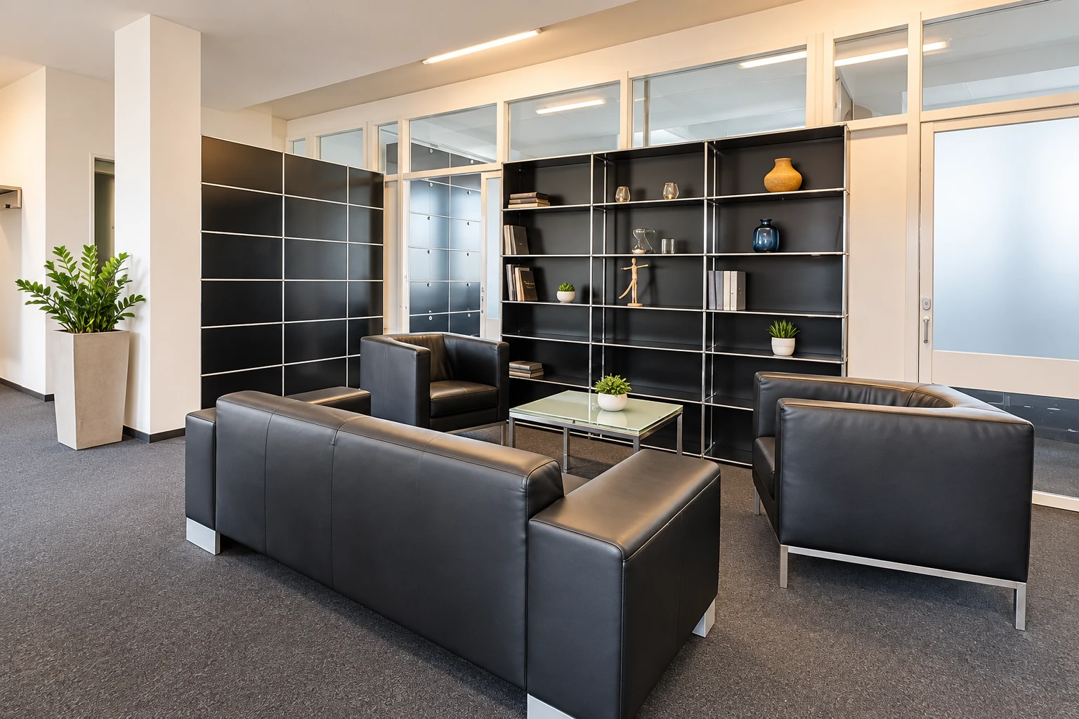 Einladende PrimeDesk-Lounge mit schwarzen Ledersesseln, Sofa und Glastisch